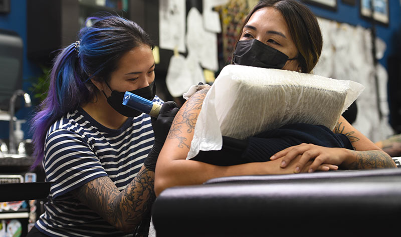 Ariyana tattooing a client